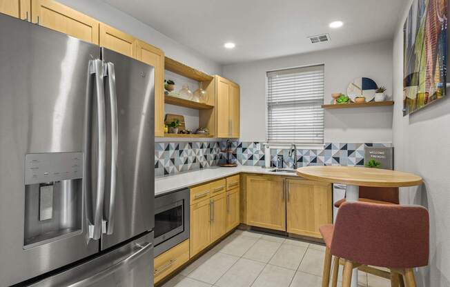A kitchen with a stainless steel refrigerator and wooden cabinets.