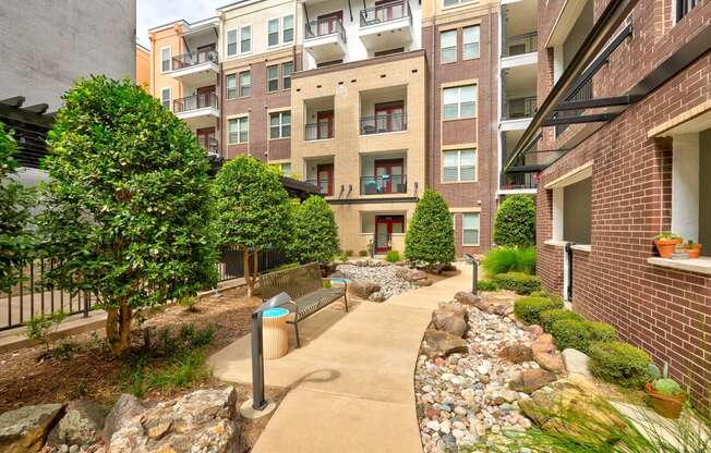 a walkway with benches in front of an apartment building