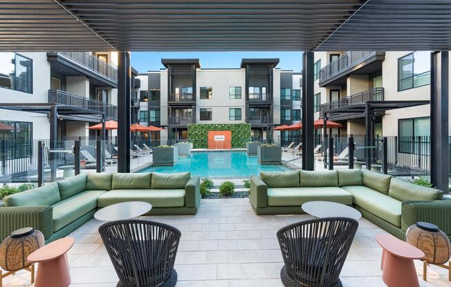 A covered poolside lounge at Modera Higley Commons, designed for relaxed gatherings with layered seating, shaded comfort, and a refined outdoor atmosphere.