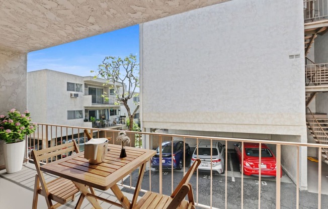 a balcony with a table and chairs and a parking lot