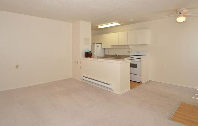 an empty living room and kitchen with a stove and refrigerator