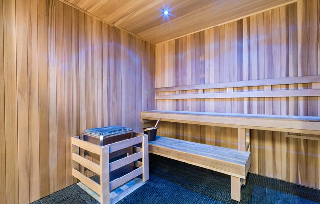 Wood-lined sauna with tiered bench seating and ambient lighting, offering a warm retreat for recovery and post-workout relaxation.