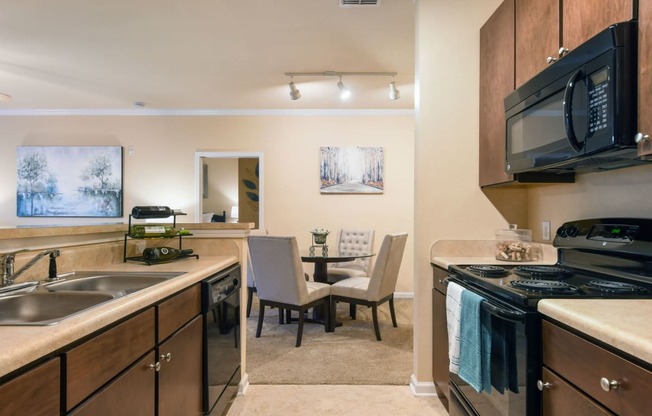 a kitchen with a stove and a sink and a dining room
