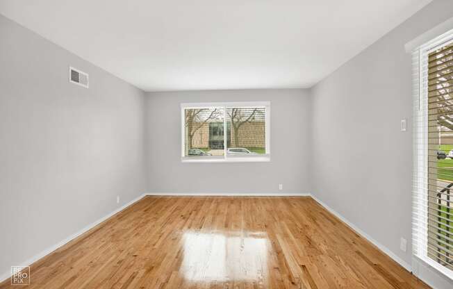 a bedroom with a large window and hardwood floors