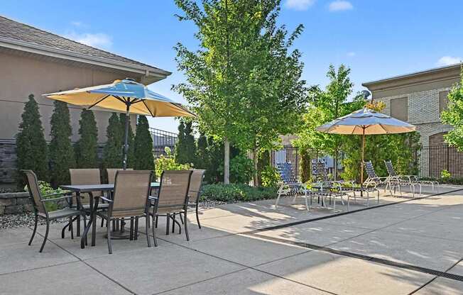Pool amenity space with chairs, table and umbrellas at The Residences at Toscana Park in Granger, Indiana.