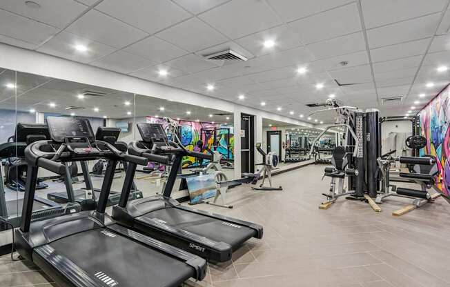 A gym with treadmills, weights, and exercise equipment.