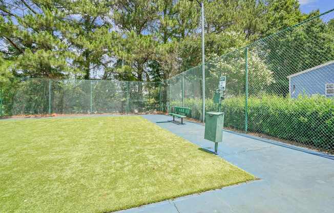 A green fenced area with a bench and a trash can.