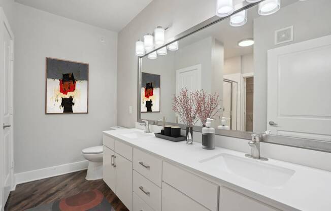 A bathroom with a white counter top and a painting on the wall.