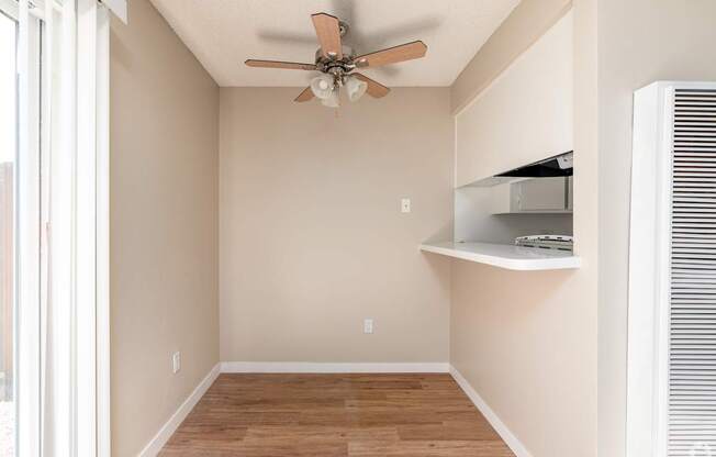 A room with a ceiling fan and a window with blinds.
