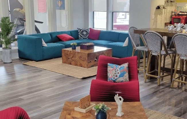 Fusion Orlando apartments clubhouse with large blue low-profile sectional and wooden block coffee table on a braided jute rug.