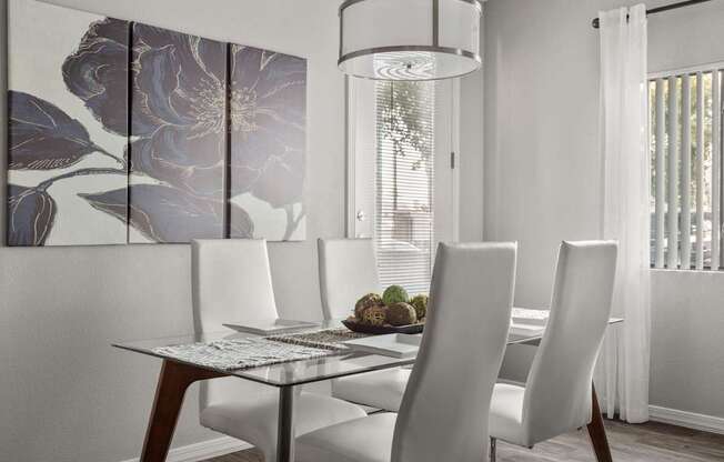 A dining table with four chairs and a decorative wall hanging.