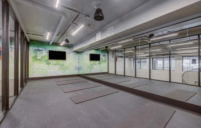 an empty room with mats on the floor and televisions on the wall