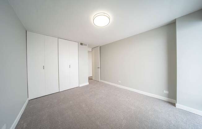 a bedroom with white walls and carpet and white cabinets