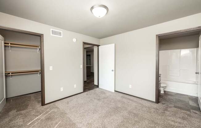 a bedroom with a closet and a bathroom with a mirrored door