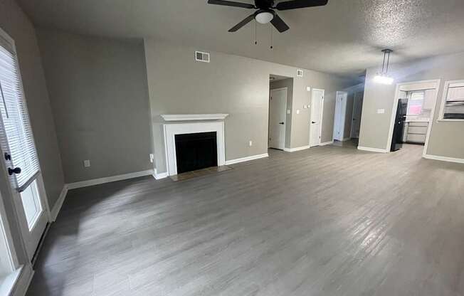 A spacious room with a fireplace and a ceiling fan.