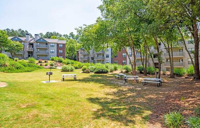 a park with benches and trees in front of an apartment building