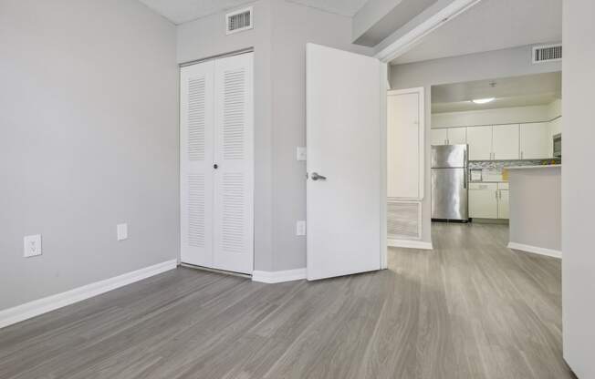 the living room and kitchen of an apartment with white walls and wood flooring at Pembroke Pines Landings, Pembroke Pines, Florida, 33025