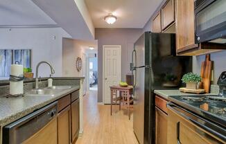 Kitchen with ceiling light, stainless steel appliances, dishwasher, oven, stove top, microwave, wood floor and wood cabinets