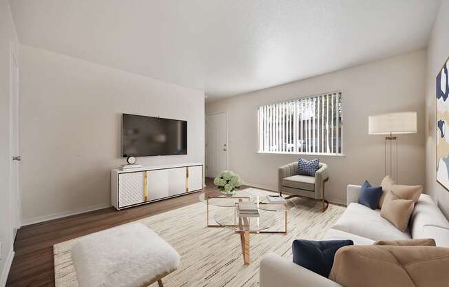 A living room with a white sofa, a white chair, a wooden coffee table, and a television on a cabinet.