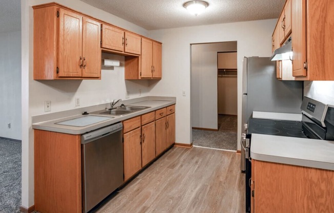 an empty kitchen with wooden cabinets and stainless steel appliances