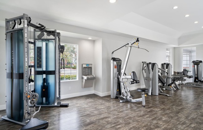 a gym with weights and cardio equipment in a home with a window