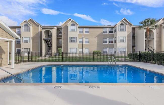 A large apartment complex with a pool in front.