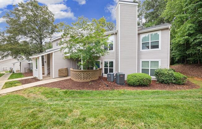 the front of a white house with a yard and trees at Chapel View Apartments in Chapel Hill, NC