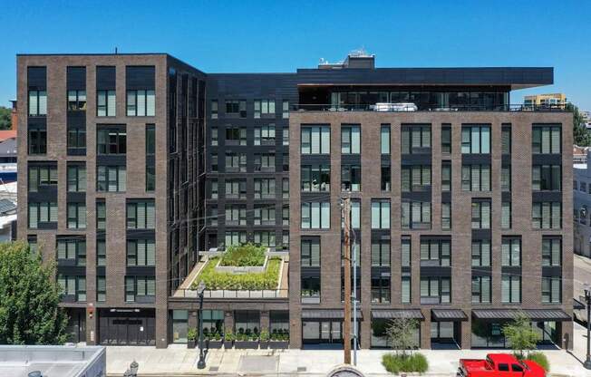 A modern building with a black facade and a green garden in front.