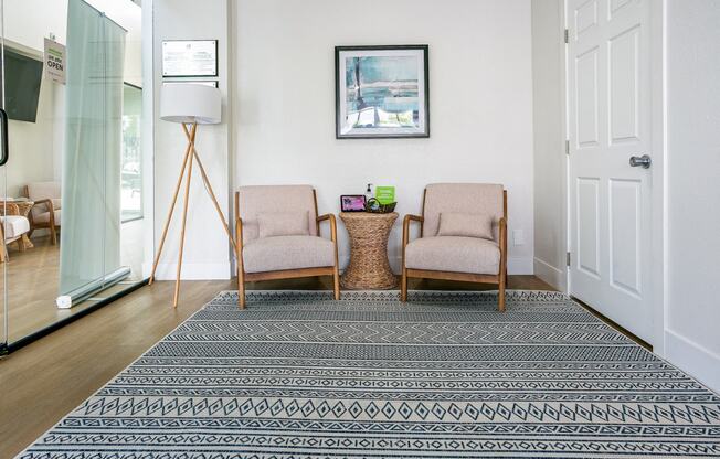 a living room with two chairs and a rug on the floor