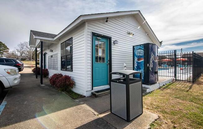 a small white building with a blue door and a trash can at Cleo Apartments, Alabama, 35611