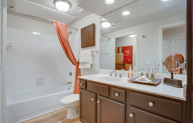 View of Bathroom with Plank-Wood Flooring, Garden Tub, and Large Mirror at Raveneaux Apartments