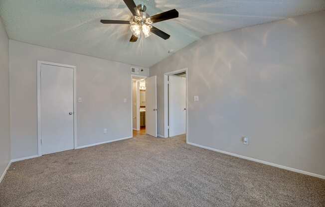 an empty living room with a ceiling fan and white walls