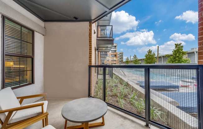 a balcony with a view of a river and a patio with chairs and a table at St. Elmo Apartment in Austin, TX
