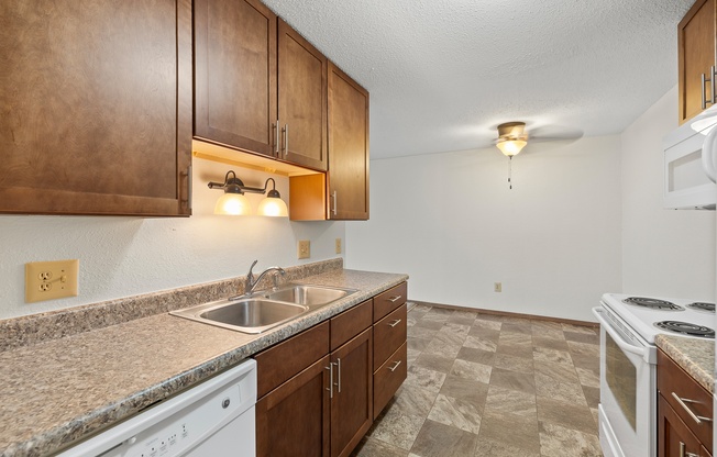 A kitchen with brown cabinets and a white dishwasher.