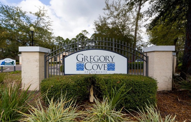 A sign that says Gregory Cove Apartments is displayed on a gate.