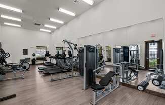 a gym with cardio equipment and mirrors on the wall