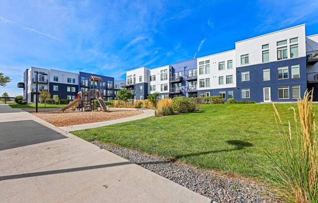 A modern apartment complex with a playground in the foreground.
