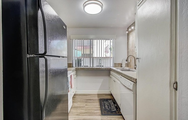 a kitchen with white cabinets and a black refrigerator