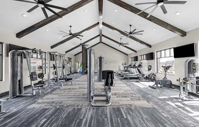 a gym with weights and cardio machines and ceiling fans