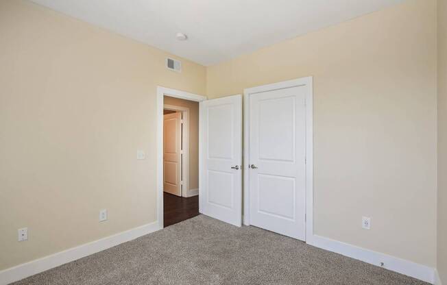 A room with a carpeted floor and two white doors.