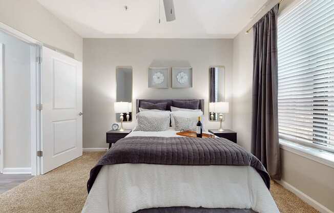 A bedroom with a bed, two lamps, and a clock on the wall.