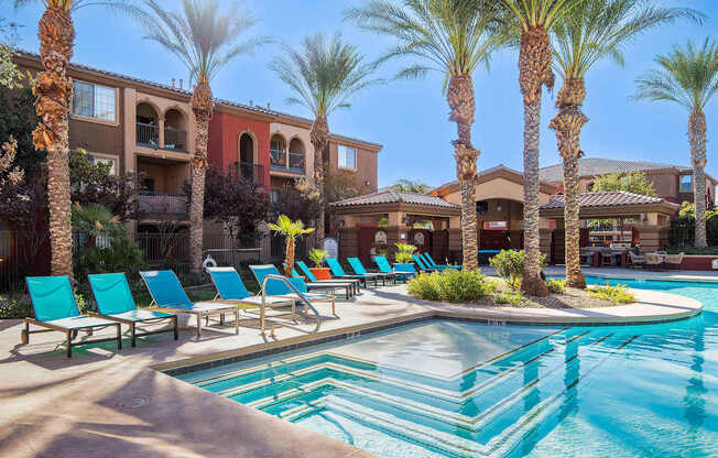 a swimming pool with blue chairs and palm trees