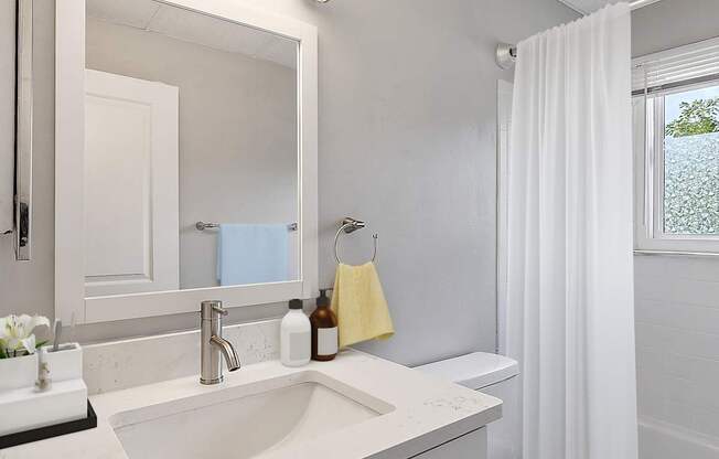 A white bathroom with a sink, toilet, and mirror.
