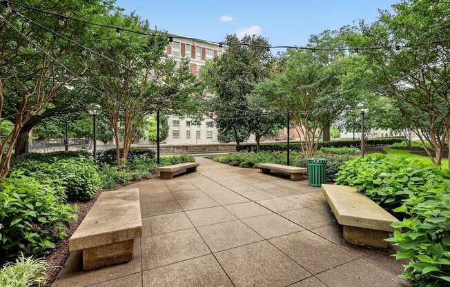 A park with benches and trees in the foreground and a building in the background.