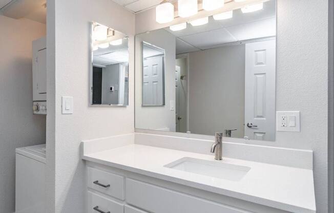 A white bathroom vanity with a sink and mirror.
