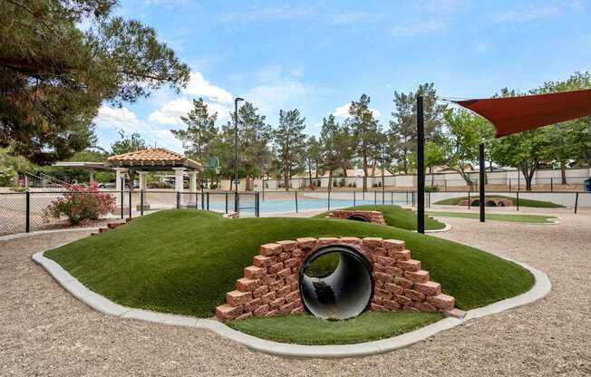 A playground with a tunnel made of bricks.