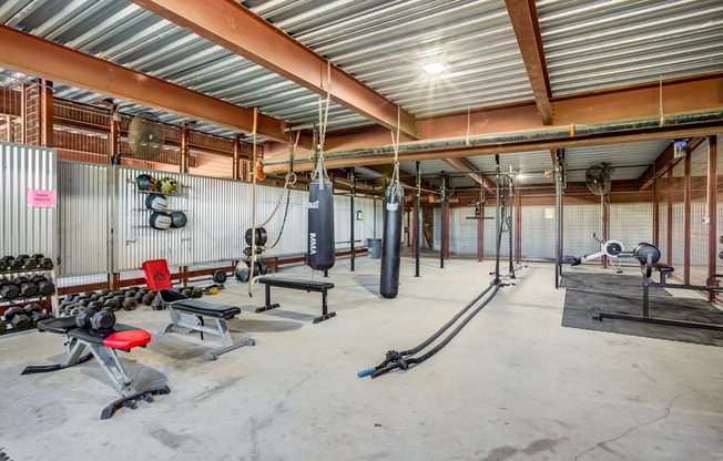 A gym with a variety of equipment including weights and benches.