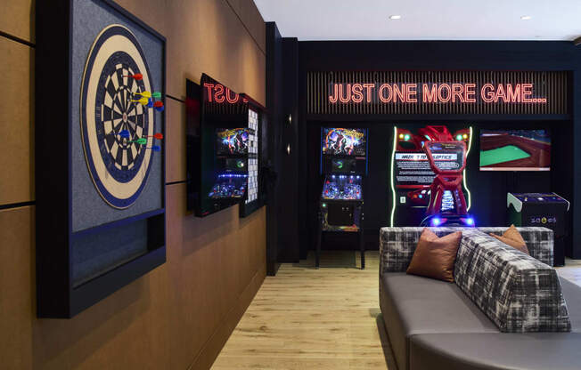 a room with a couch and a dart board and a game on the wall