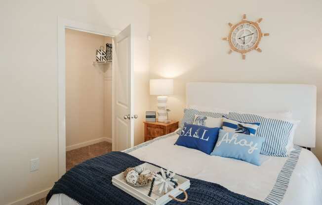 A bedroom with a bed, a clock, and a lamp.