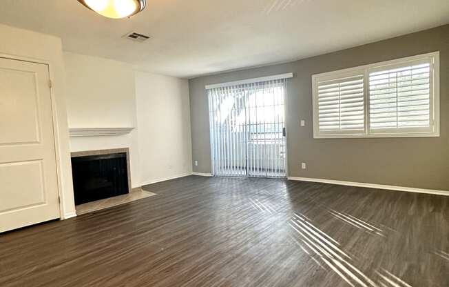 an empty living room with wood flooring and a fireplace